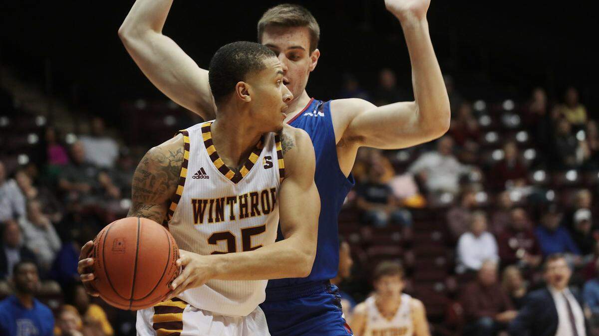 Winthrop’s Josh Ferguson looks for an opening around Presbyterian’s Ben Drake in February 2019.