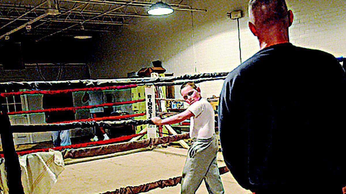 Mike Englert helps train a boy named Robert, 7, at the Rock Hill Boxing Club last week. Englert, a Rock Hill police officer, grew up on the tough streets of Rochester, N.Y., and used boxing to turn his life around. Above right, Englert demonstrates a boxing move.