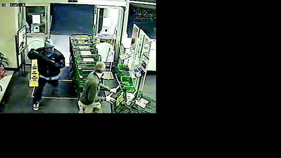 The still image above from a video shows the masked suspect, left, in Thursday's robbery of the Lowes Foods near Tega Cay.