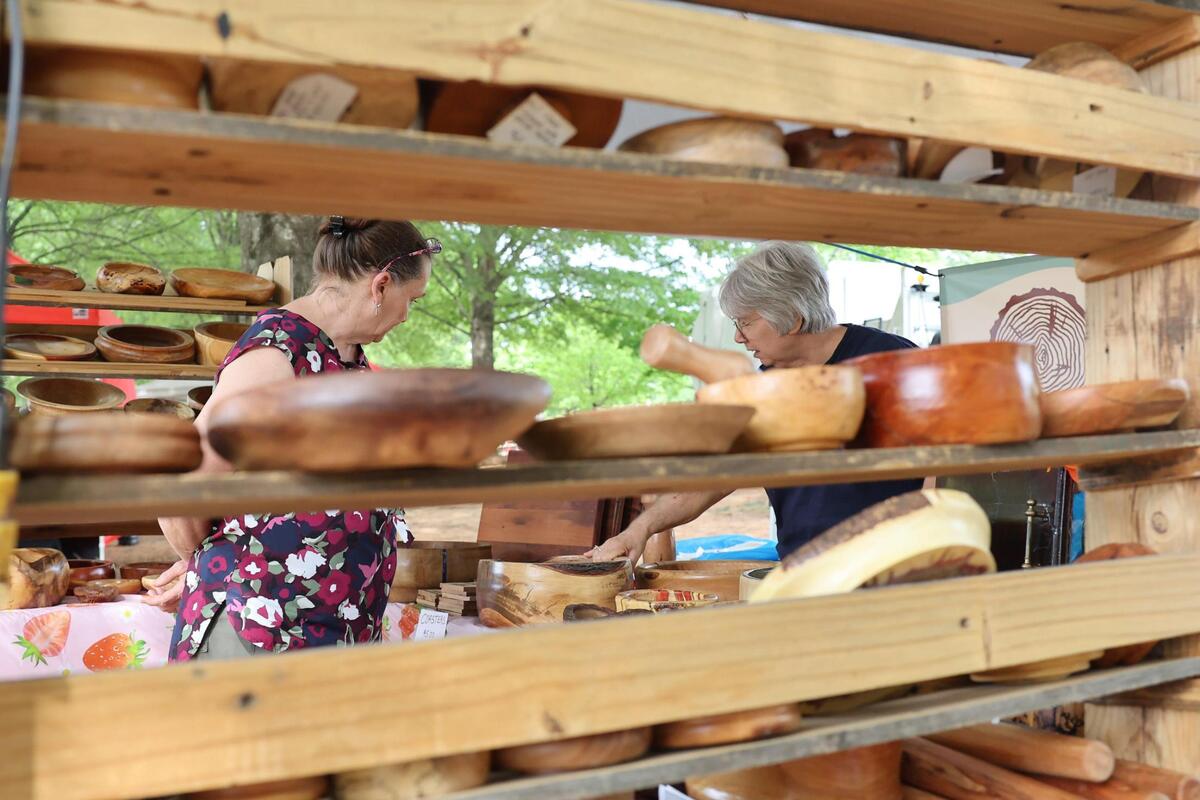 Debbie Towles, left, looks at wooden bowls as Toni Peterson explains how they are made Friday at the Strawberry Festival in Fort Mill, S.C.