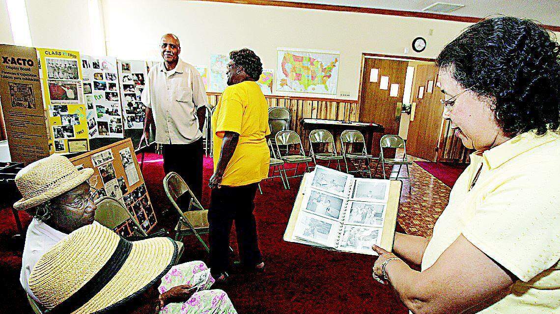 Elizabeth Patterson White, right, George Fish Class of 1959, shows old pictures from the school to Jean Watts, bottom left, and Ruth Watts, top left, at the Volunteer Faith Center in Fort Mill on Tuesday. In the background, Rev. Phillip Cargile, left, and Naomi Gilmore Stanley, Class of 1946, look at displays of pictures from the school.