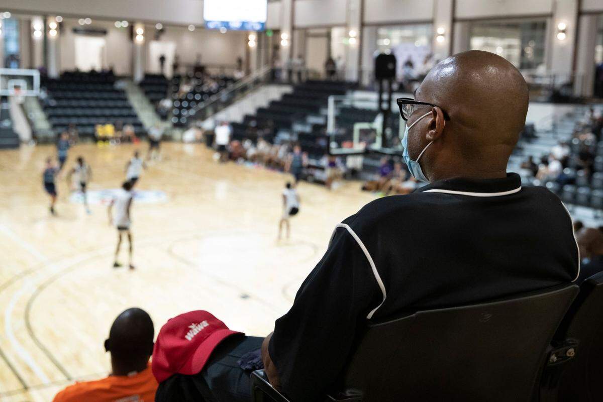 A spectator wears a mask and watches a game on the arena court inside the Rock Hill Sports and Event Center on Saturday, Aug. 1.