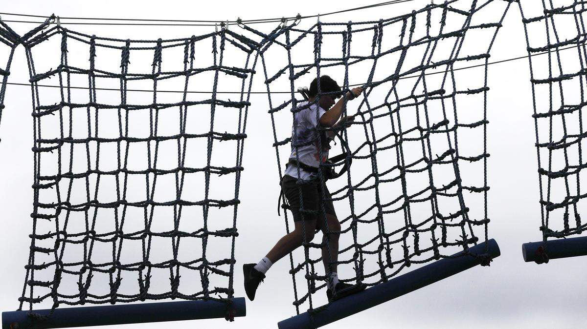 14-year-old Caleb Adkins of Monroe, N.C. walks along a rope bridge before ziplining Tuesday at Mr. Putty’s Fun Park in Tega Cay.