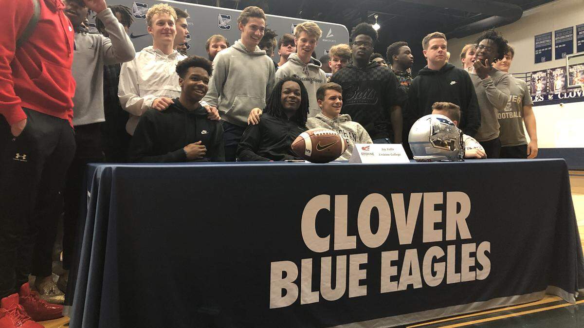 The Clover football team’s upperclassmen pose for a picture around their fellow senior, Jay Falls, on National Signing Day (Wednesday, Feb. 5, 2020).