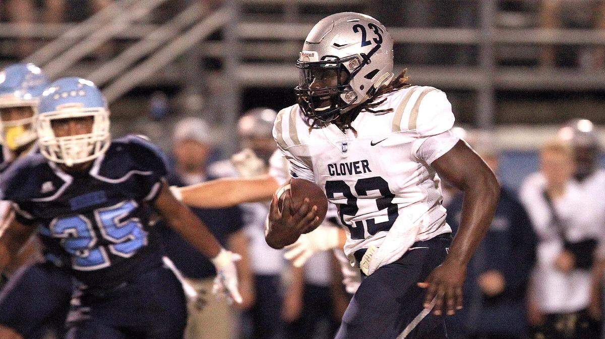 Clover’s David Hall breaks into the open field for a 60-yard touchdown run as Hunter Huss’ Anthony Dye give chase during their game  Friday night.  [JOHN CLARK/THE GASTON GAZETTE]