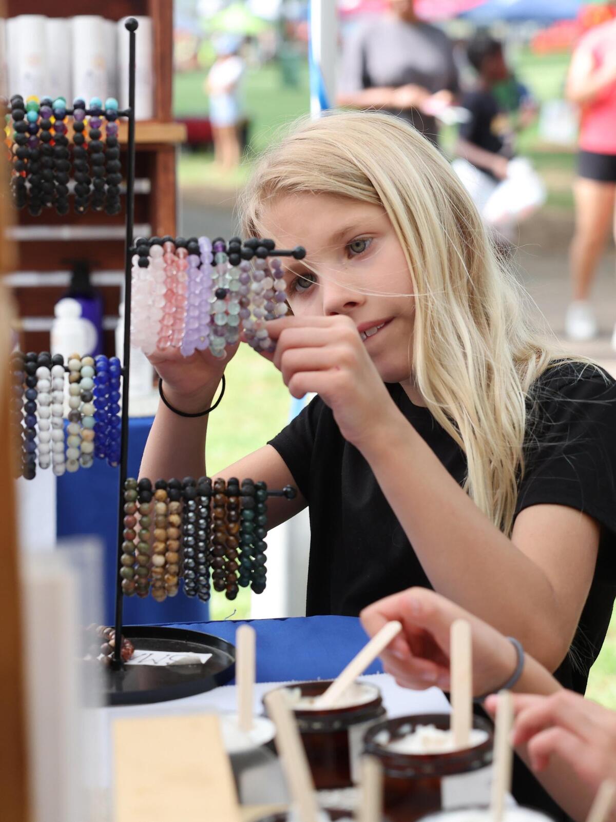 8-year-old Liana Dicks of Fort Mill looks at bracelets Friday, May 2, 2025 at Fort Mill’s Strawberry Festival.