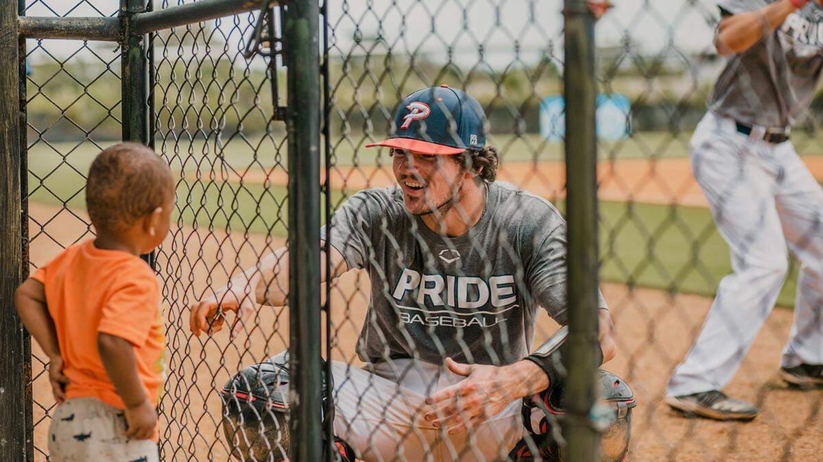 Herald file: A 2021 summer baseball player for the Piedmont Pride, which is now called Kingsmen Baseball, talks to a child through fencing on a mission trip to the Dominican Republic. Kingsmen Baseball is based in Rock Hill.