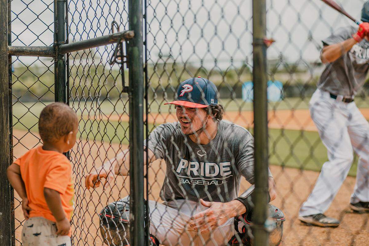 Piedmont Pride baseball player Justin Stewart talks to a child through fencing at the Rock Hill team’s recent mission trip to the Dominican Republic.