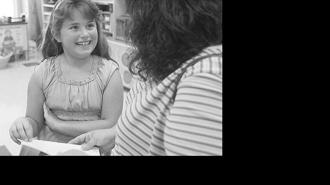 Above, Brittany Wright, a third-grader at India Hook Elementary School, shows her mother, Glenda Wright, her notebook at the school's dedication Sunday. At left, fourth-grader Rebecca Evans shows her grandfather, Bruce Morris, and her mother, Tiffany Evans, a book during the dedication.