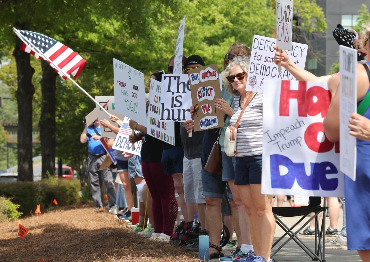 Demonstrators hold signs Saturday at the York County Rising protest in downtown Rock Hill.