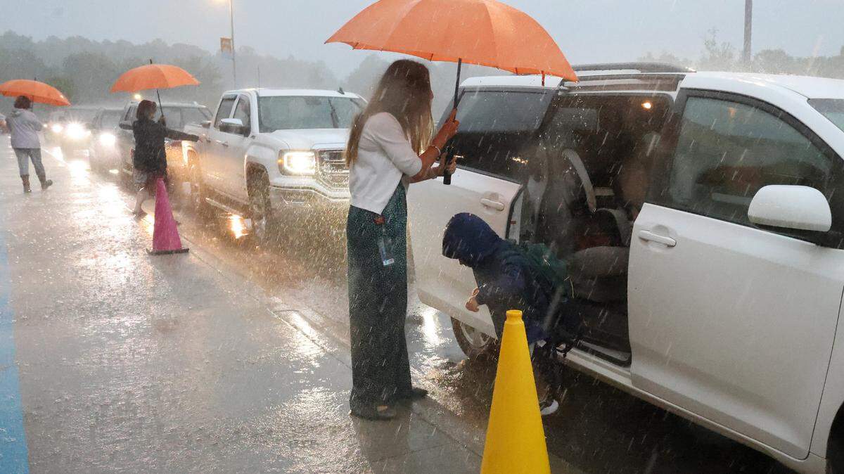 School staff at Fort Mill’s River Trail Elementary School try to stay dry as they help kids out of cars on the first day of school. The district held school despite Tropical Storm Debby soaking the area.