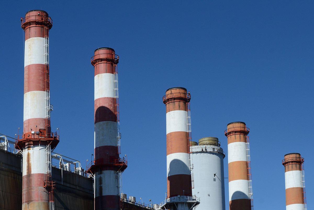 Much plainer to the eye than the five red-striped stacks at Allen Steam Station in Belmont it is the only smokestack still in use. High up on a scaffold works prepare for the eventual demolition, without explosives, of all six stacks.