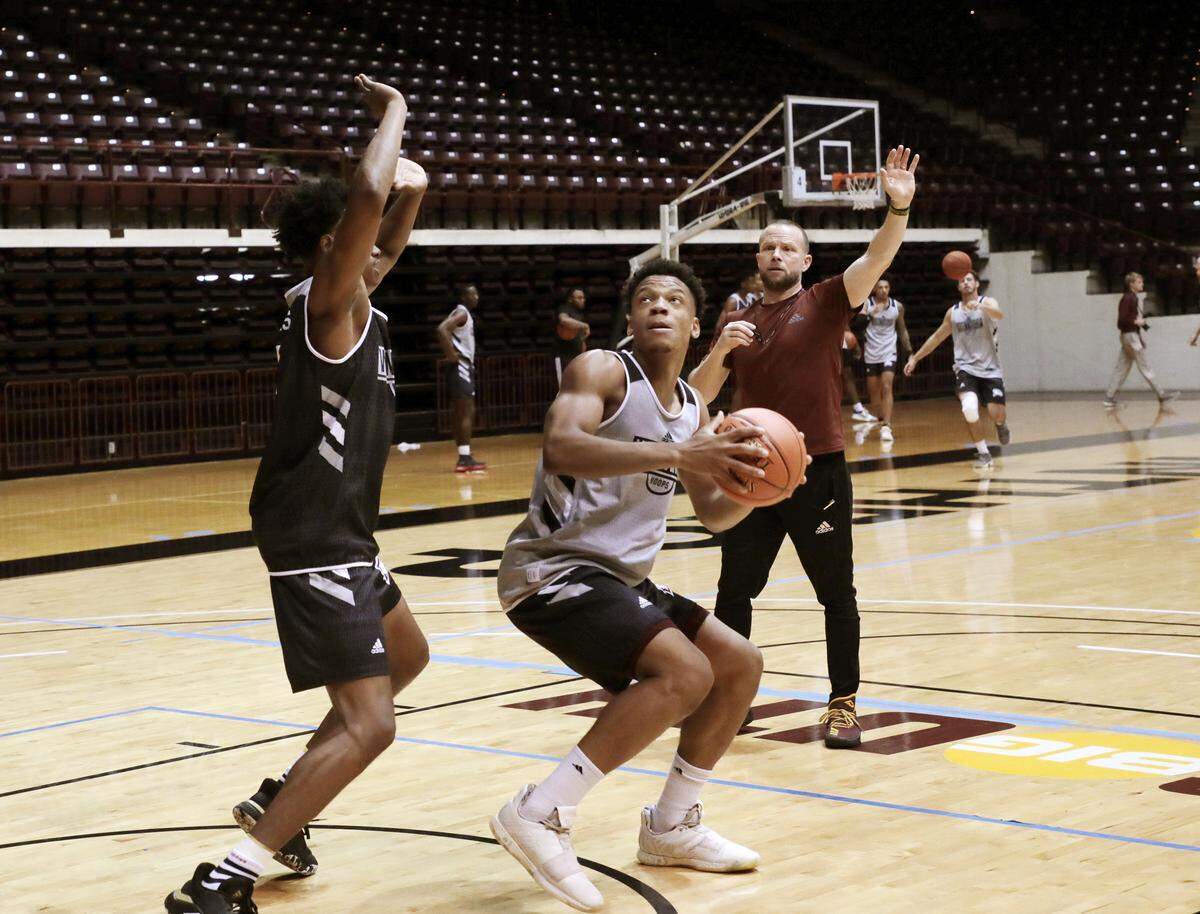Winthrop University men’s basketball coach Pat Kelsey observes Michael Anumba, middle, drive to the basket around Adonis Arms during practice Thursday.