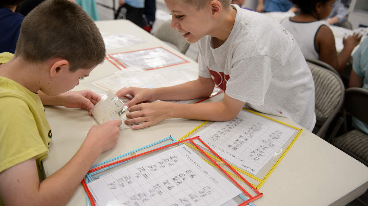 Twin brothers Benjamin and David Miller examine an antique postcard written by a Miller from generations ago.