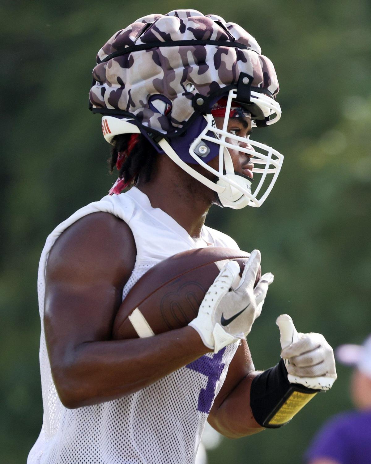 A Northwestern varsity football player runs with the ball Friday during practice.