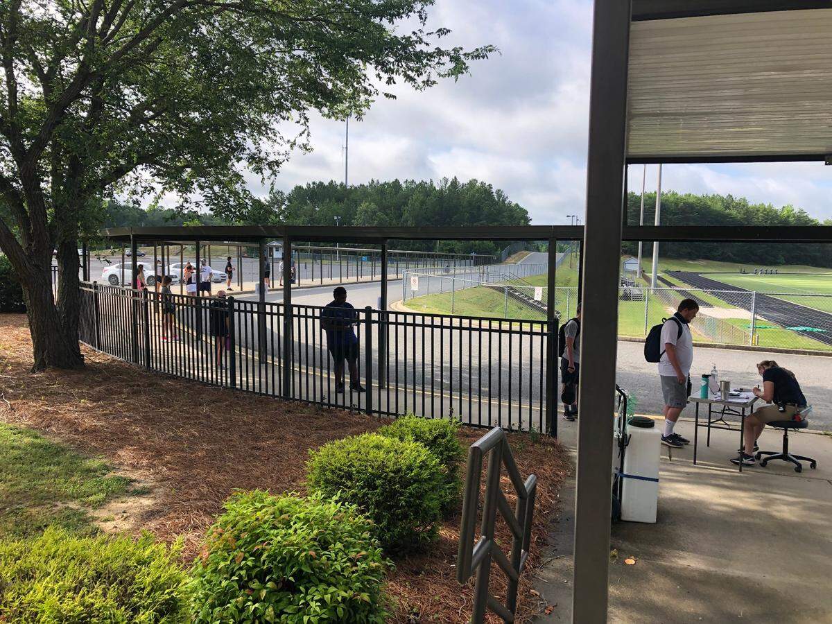 Clover assistant athletic trainer Katherine Kiser verifies that students have filled out the proper paperwork and checks for COVID-19 symptoms prior to Clover’s first day of summer workouts on Wednesday.