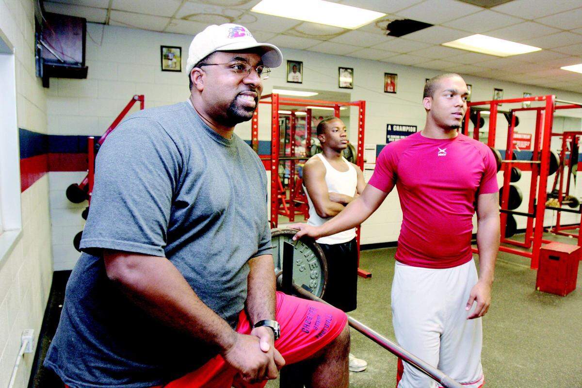 New Chester High School football coach Maurice Flowers, left, talks with some of his players in the weight room at the high school. Players Maurice Caldwell, center, and Brandon Nash listen.