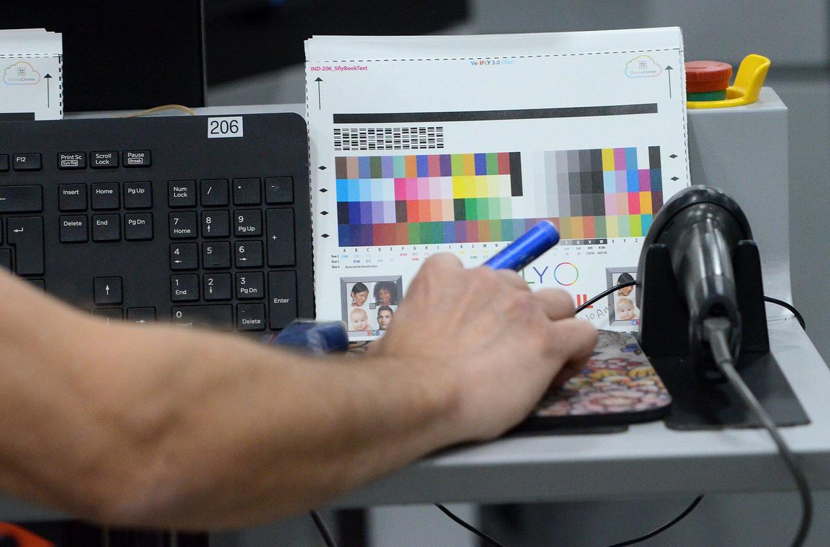 Carl Proia, a digital press operator, adjusts the settings on a sheet for a photo book at Shutterfly.