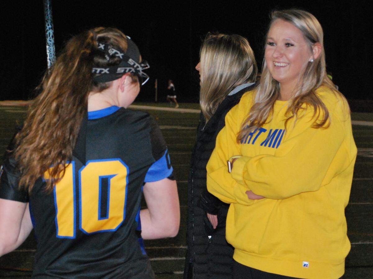 Fort Mill girls lacrosse coach Kirsten Terry, in yellow, talks with Paige Wasiela, No. 10, before a recent game.