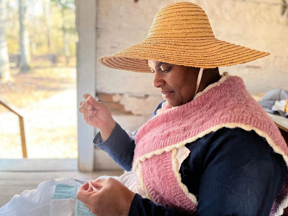 Interpreter Kenya Lane works on a quilt she is making at Historic Brattonsville on Sat., Feb. 12, 2022. The site is holding its “By Way of the Back Door” to show what life was like for enslaved people living there during the 18th and 19th century.
