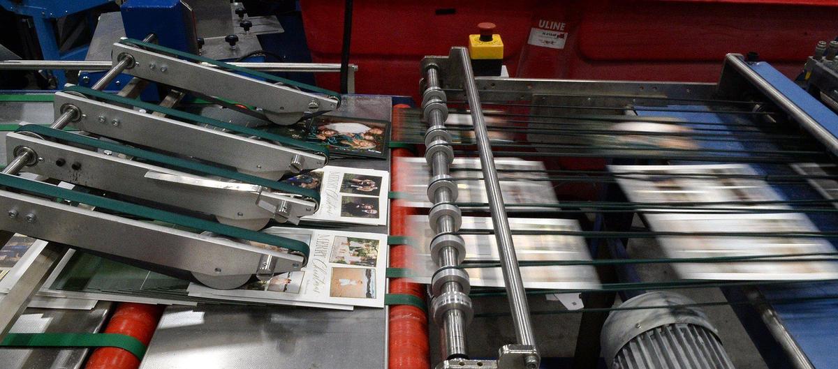 Photo cards fly through a cutting machine before packaging at Shutterfly in Fort Mill, S.C. The production site makes millions of cards per day during the last month of each year.