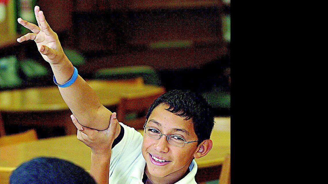 Above, Jonathan Perez raises his hand in Betty Jordan's sixth-grade class at Sullivan Middle School recently. At right, Jordan, the school's media specialist, teaches a class how to use Movie Maker.