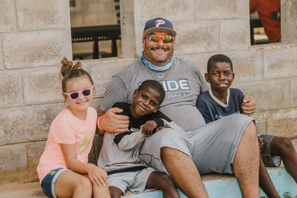 Matt Deegan, center, hugs some of the kids in the orphanage Piedmont Pride visited on its mision trip to the Dominican Republic.