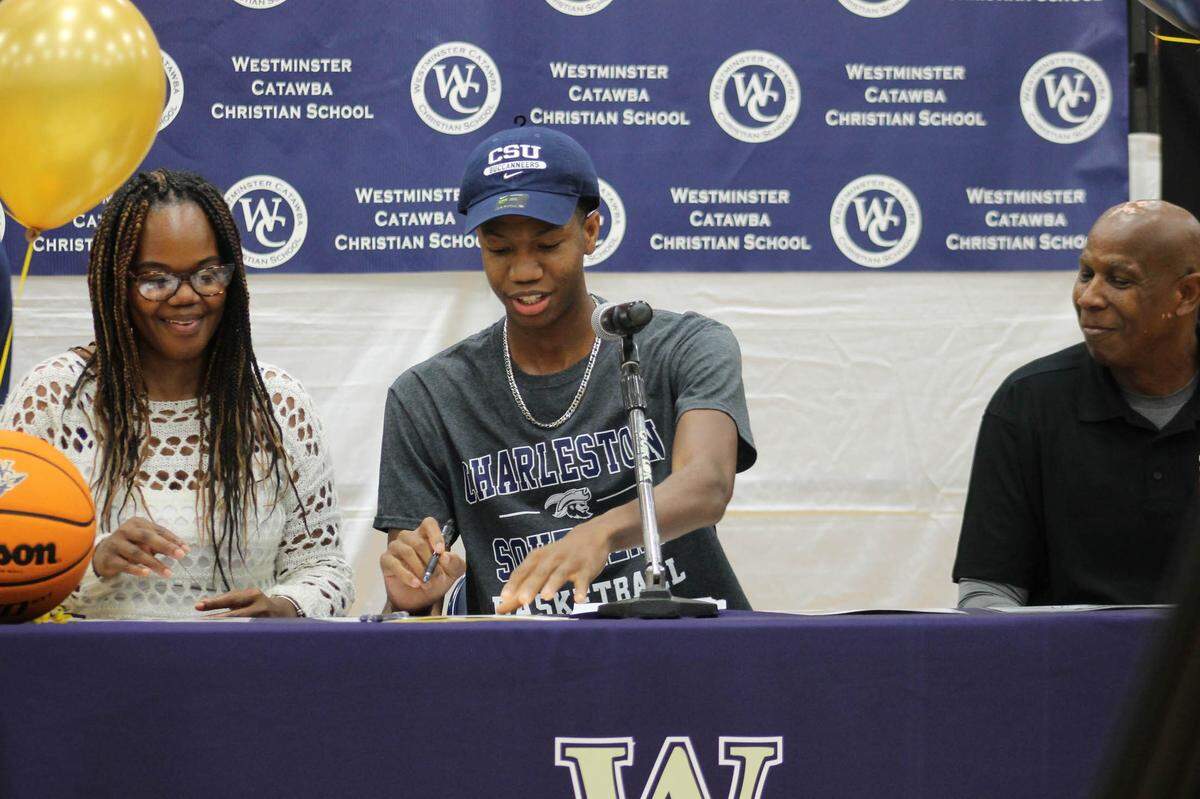 AJ Hamrick sits with his mother, Nicole (left), and father, Adrian Hamrick Sr. (right) as he celebrates his signing to Charleston Southern.