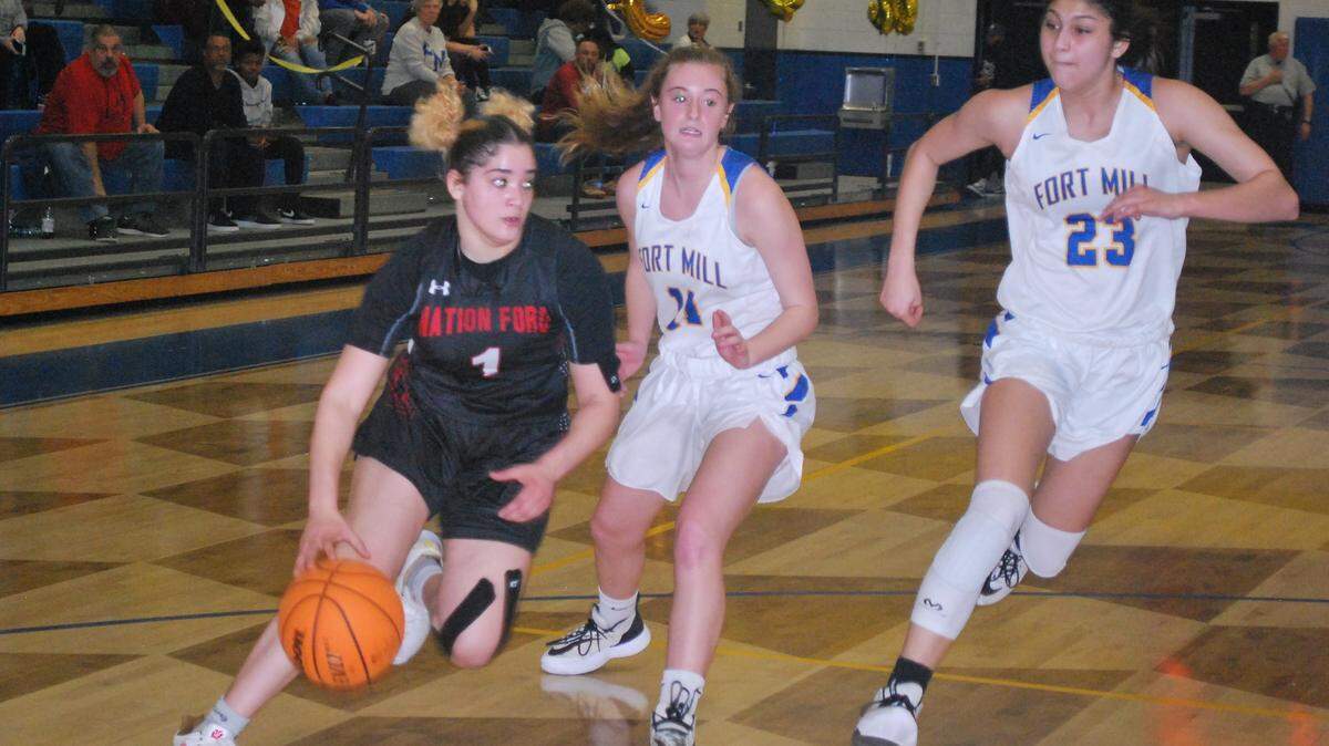 Nation Ford’s Adrienne Ruffalo drives to the basket past two Fort Mill defenders. Ruffalo led the Falcons over rivals Fort Mill to clinch a spot in the playoffs in 5A.