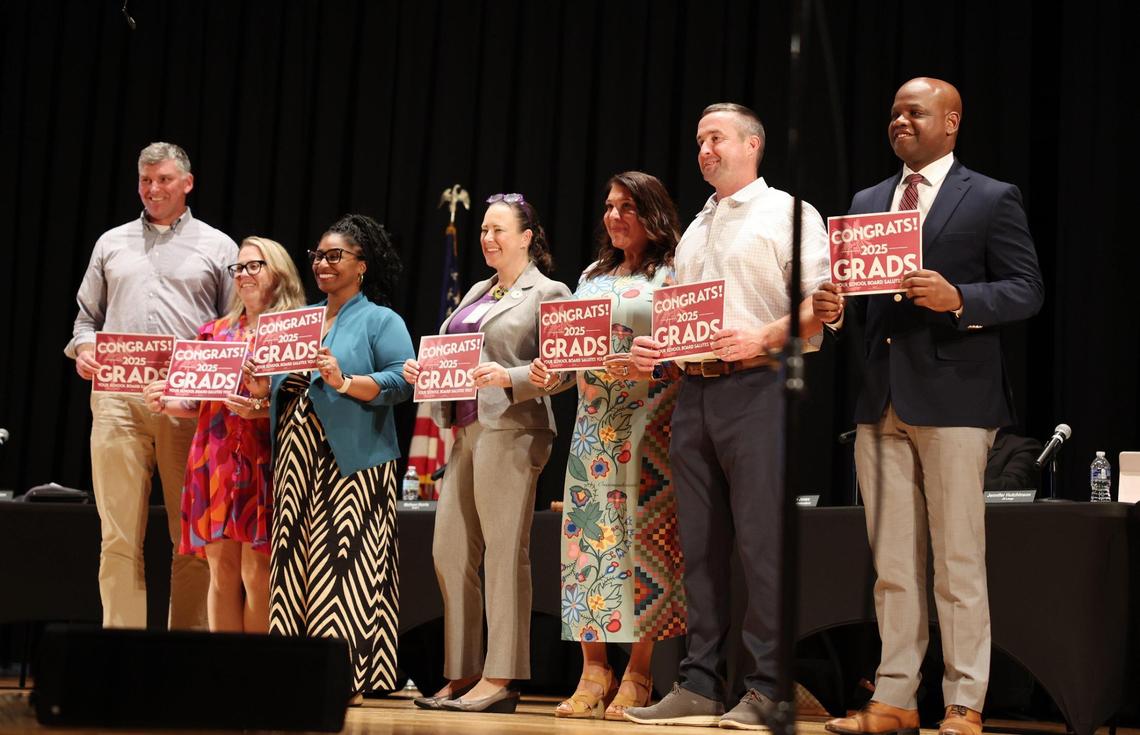 The Rock Hill School Board poses with congratulatory signs Tuesday at its meeting.