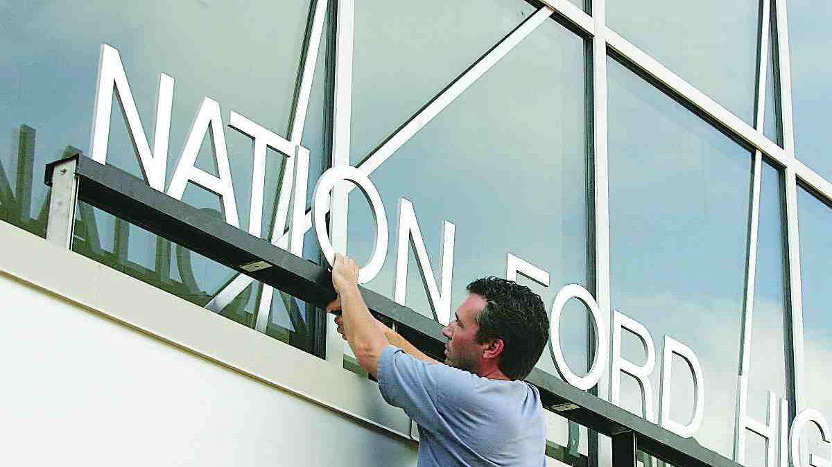 Pat Wichowski with Union Glass & Metal in Fort Mill adjusts a Nation Ford High School sign at one of the entrances to Fort Mill's newest school recently.