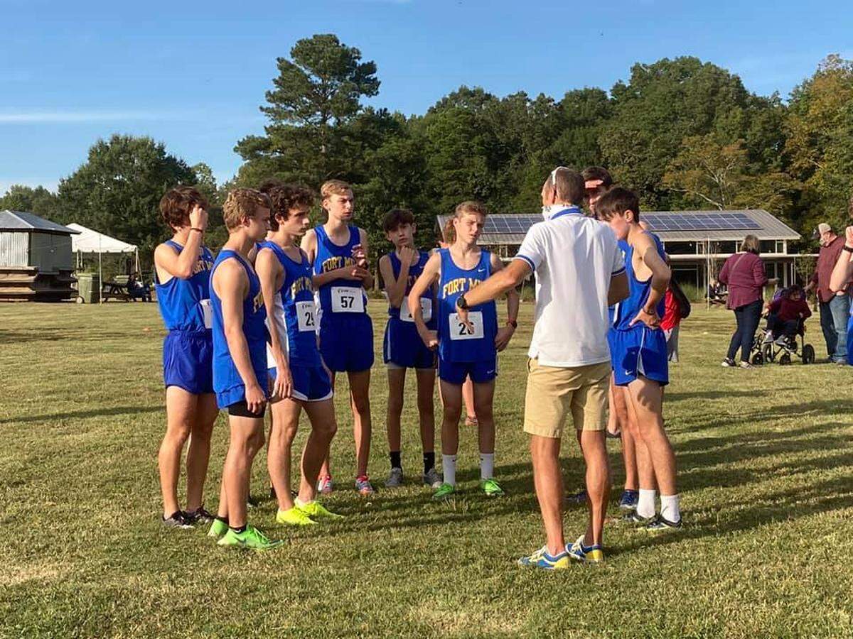 The Fort Mill boys’ team, led by head coach Lee Whitaker, gather before a recent race.