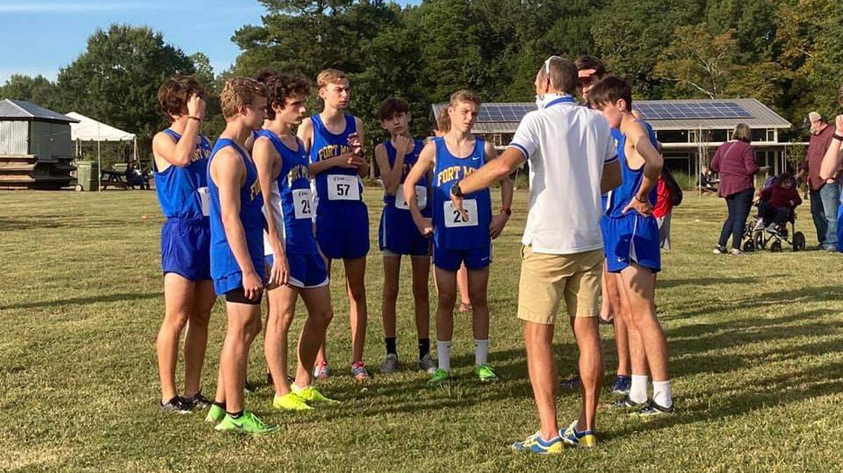 The Fort Mill boys’ team, led by head coach Lee Whitaker, gather before a recent race.
