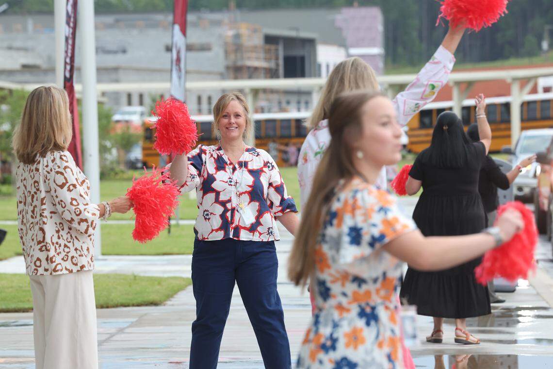 Teachers at Flint Hill Elementary School in Fort Mill, S.C. wave flags to cheer on new students Monday, Aug. 4, 2025 at the first day of school. Flint Hill opened Monday as the 21st school in the Fort Mill district. Kindergarten enrollment is down this year in the region’s largest district.