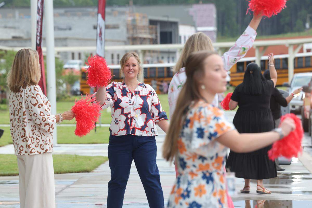 Teachers at Flint Hill Elementary School in Fort Mill, S.C. wave flags to cheer on new students Monday, Aug. 4, 2025 at the first day of school. Flint Hill opened Monday as the 21st school in the Fort Mill district.