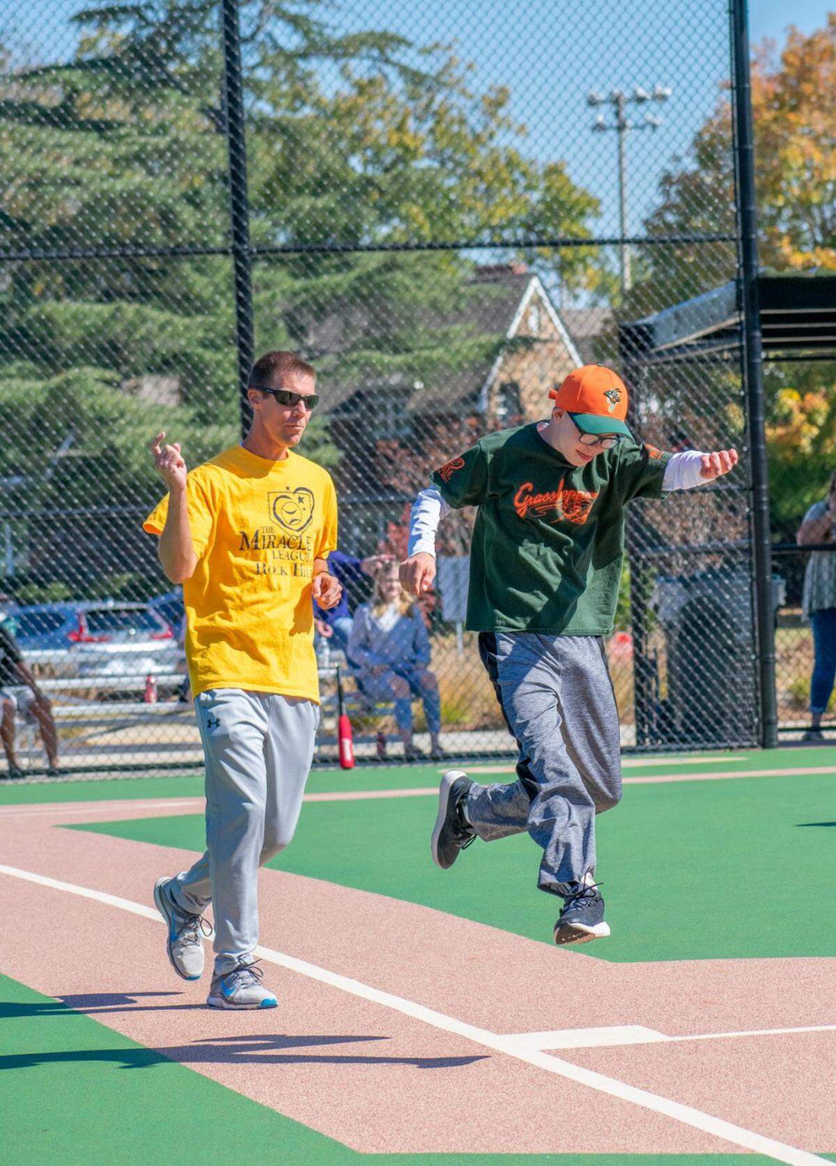 Hall Mitchell (right, green shirt) runs to first base.