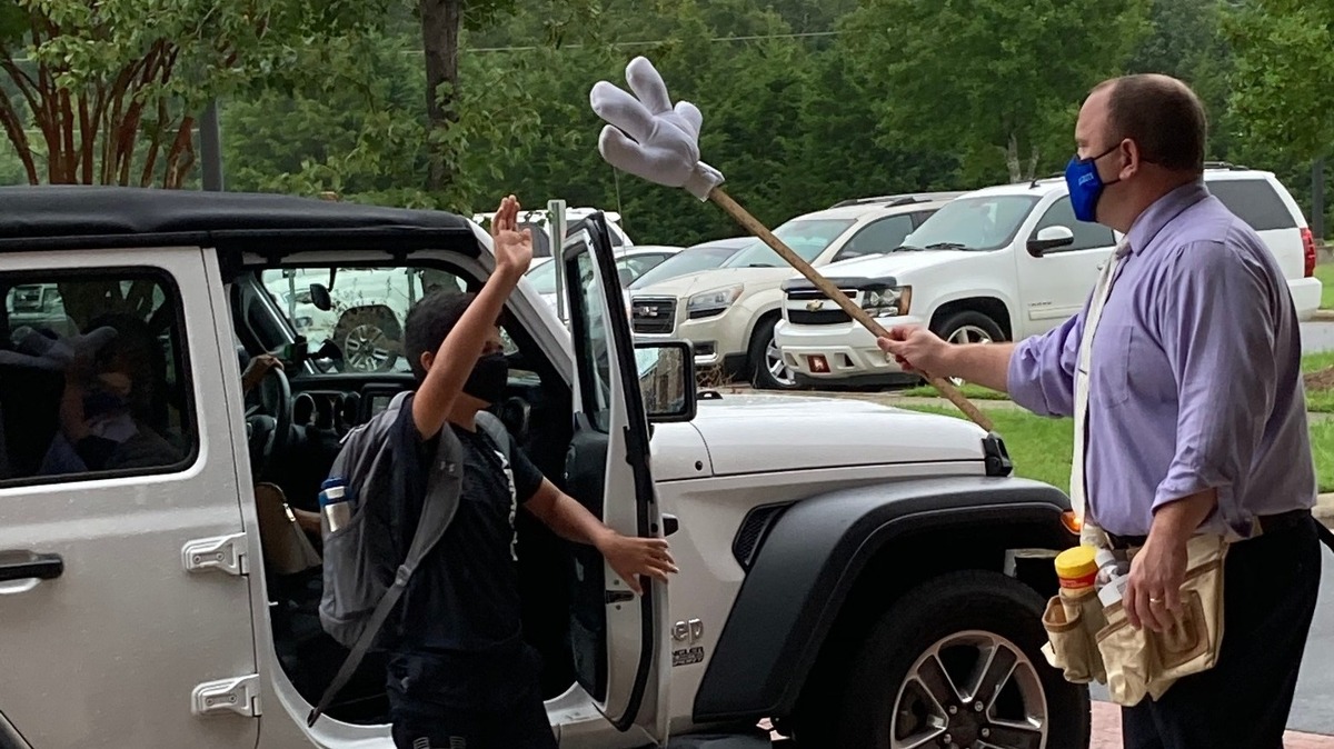 Gold Hill Middle School principal Richard Eppes offers students a “high five,” when he quickly then sanitizes between uses, on the first day of school Monday.