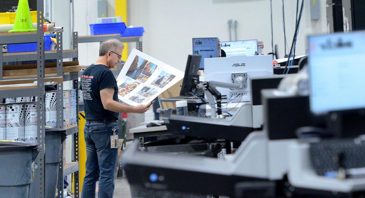 Carl Proia, a digital press operator, examines a sheet for a photo book at Shutterfly in Fort Mill, S.C.
