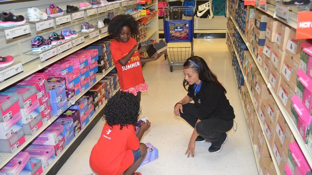 
Diamond Hope of Academy Sports + Outdoors, right, helps Kailyn Williams and ChaTiaya Moore shop for shoes. 

