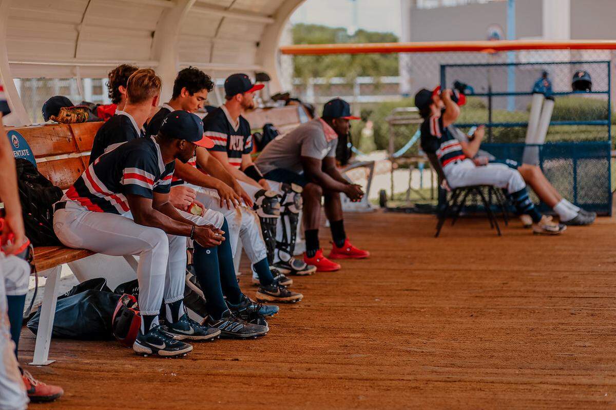 Piedmont Pride players watch one of their games in the Dominican Republic from the dugout.