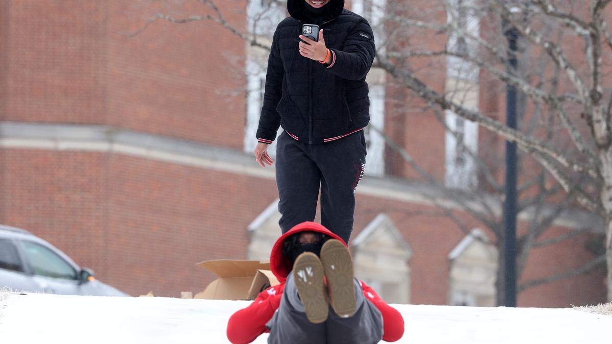 Eric McClain slides down a hill on a cardboard box Sunday, Jan. 25, 2026 at Winthrop University in Rock Hill, S.C. as Anthony Gray records. Weather reports predict more snow this weekend.