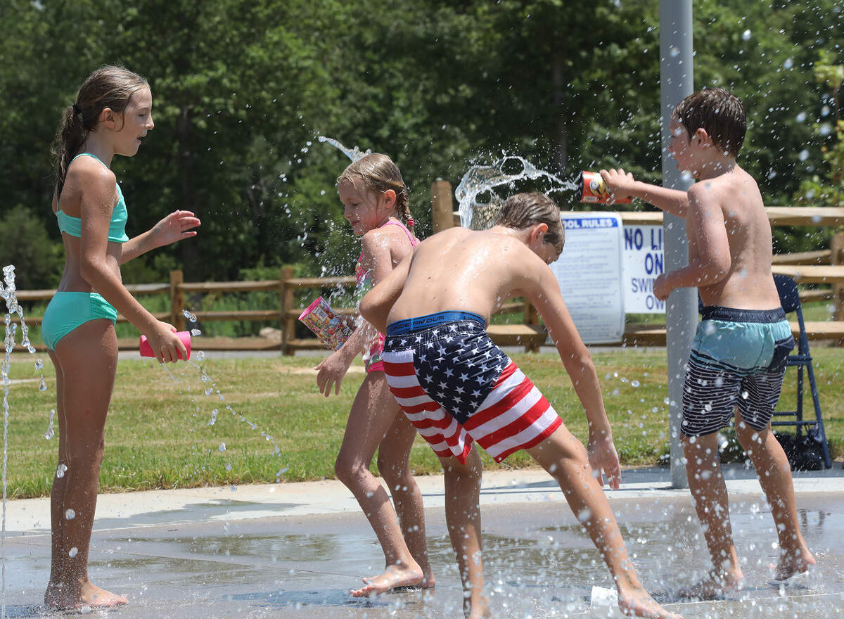 Kids dump water on each other at the splash pad at Clover’s New Centre Park.