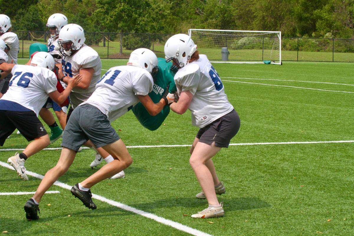 Two linemen, coached by Jimmy Wallace, run through a drill during a Legion football practice on Friday.