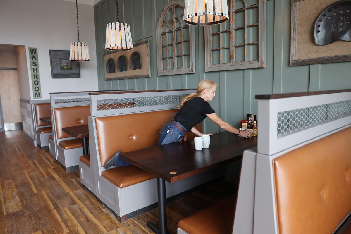 Morgan Cook, an employee at First Watch, straightens a table Wednesday at the new store on Cherry Road.