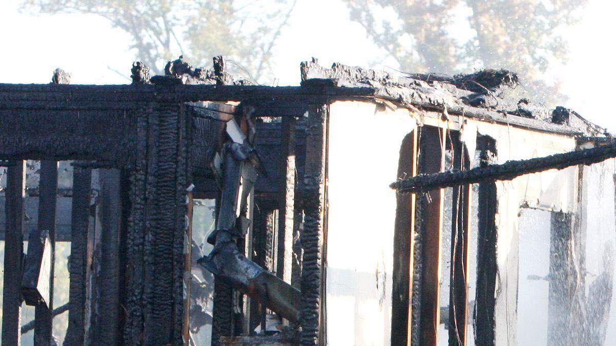 Firefighters douse hot spots at 400 Soft Winds Village Drive in Rock Hill on Thursday after a fire destroyed the home and two adjacent ones.