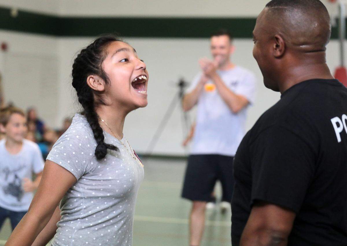 Herald 2019 file: 10-year-old Diana Luna laughs with York police officer Pierre King. A group of police officers played a game of basketball with students at the school who made progress on their standardized tests a few years ago, another instance of community impact King has had in his community over the years.