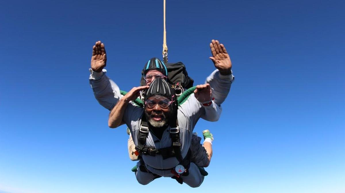 C.W. Perkins salutes while doing a tandum jump with instructor Chuck Hammond on Veterans Day Wednesday at Skydive Carolina in Chester.