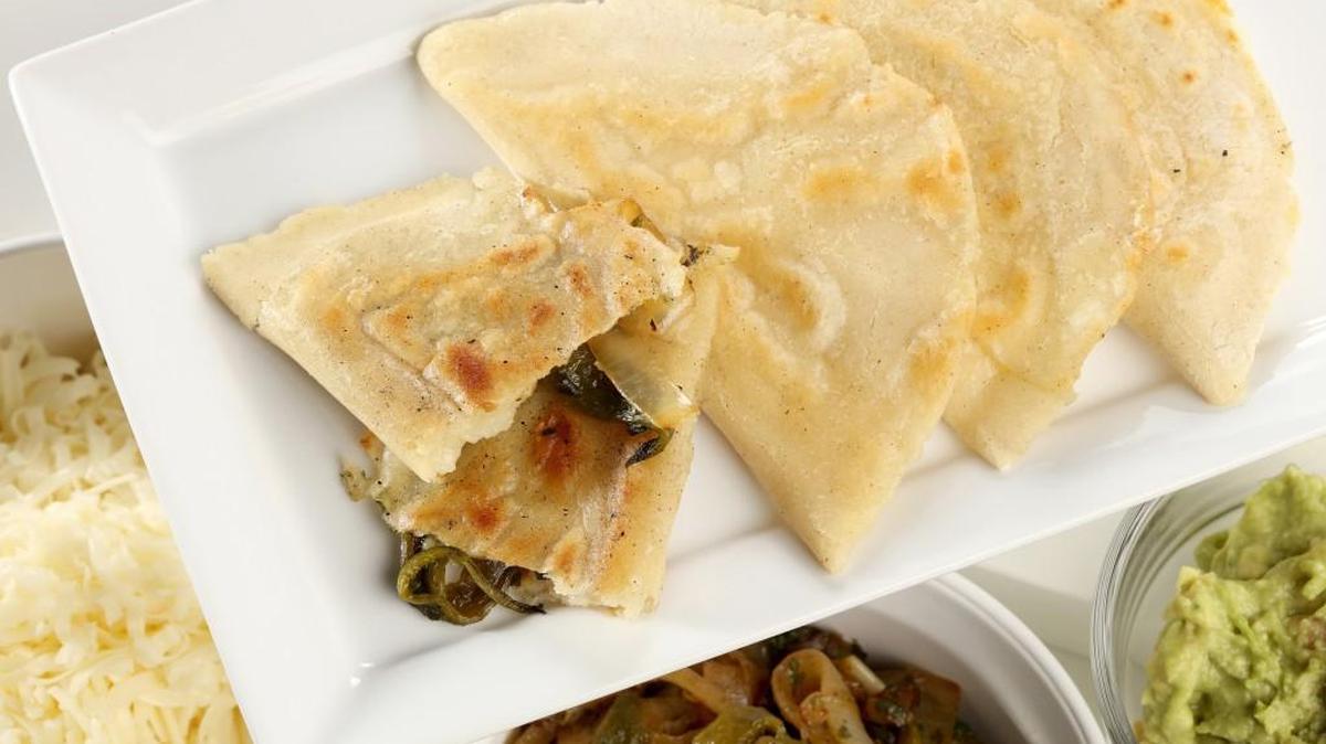 Quesadillas with fresh corn masa are filled with sauteed poblanos and onions, folded and sealed, then browned in a skillet.