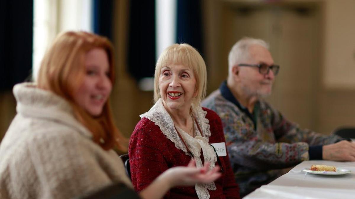 Penn Memory Center intern Genevieve, 23, left, shares coffee with Diane, 78 and Paul Cagan, 86, who has Alzheimer’s disease at the Memory Cafe at Christ Church Neighborhood House.