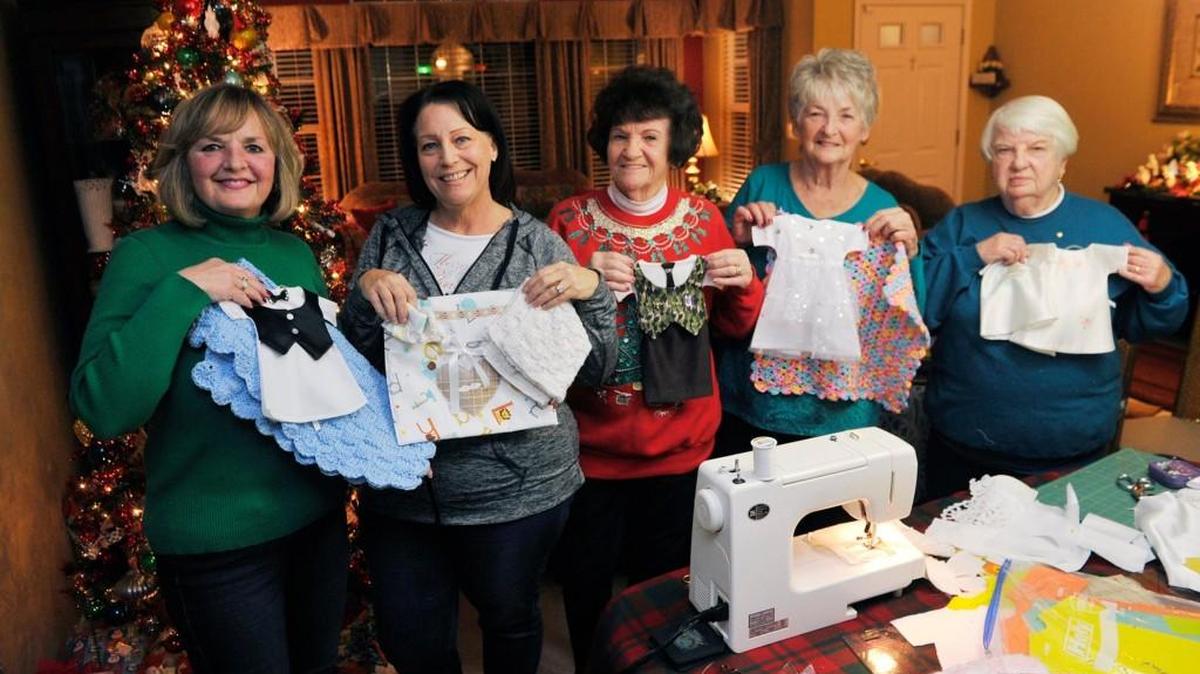 Becky Rowe, from left, Cindi Boukidis, Peggie Morgan, Antonia Rhodes, and Merry Derrick hold funeral gowns for infants that they created from donated wedding dresses.